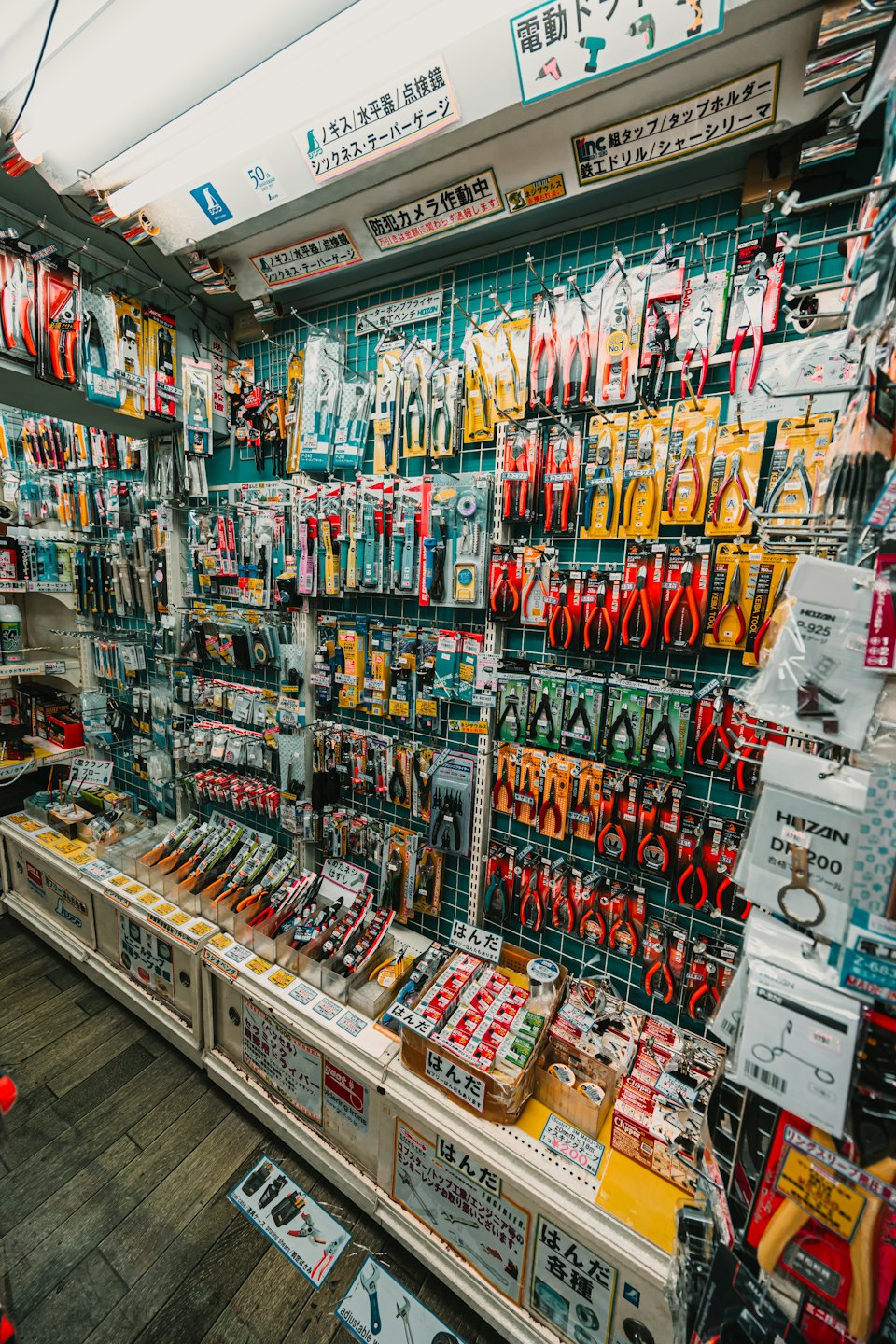 Hand tools hang on pegboards inside a Japanese hardware store.